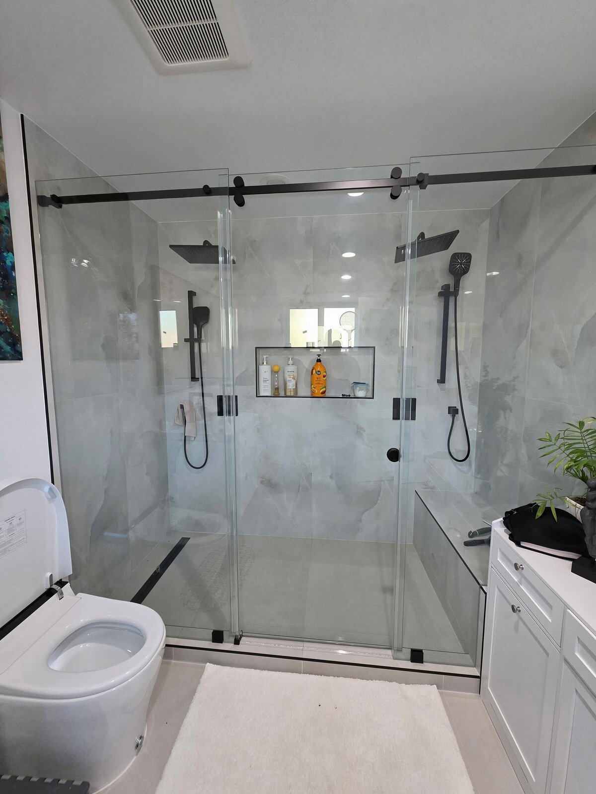 Remodeled bathroom with double walk-in shower, sliding glass doors and black fixtures
